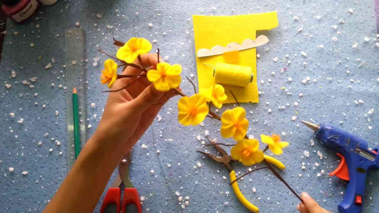 Cắt hoa mai trên giấy nhún màu vàng, mỗi cánh dài 5cm