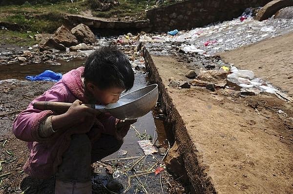 Một cậu bé đang phải uống nước ô nhiễm từ một con sông ở tỉnh Vân Nam, Trung Quốc
